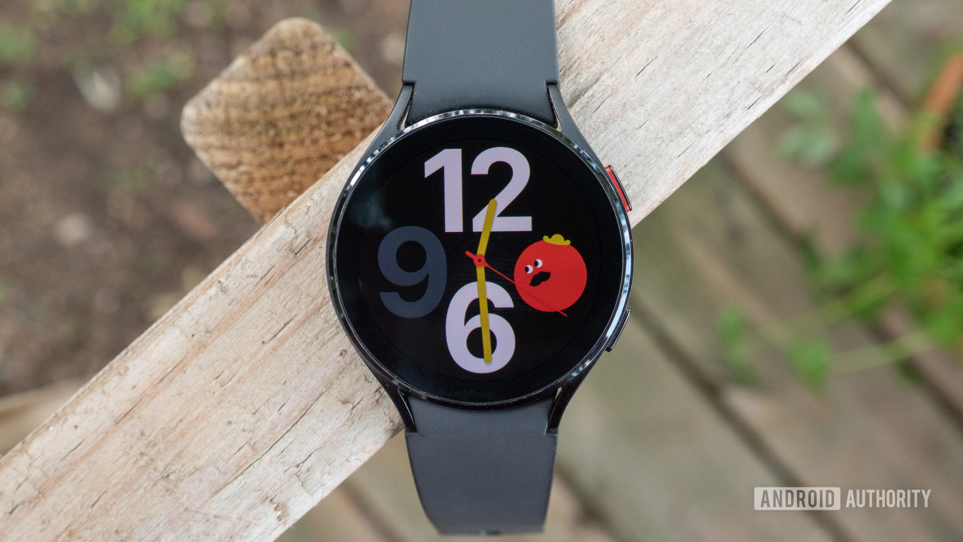 The Samsung Galaxy Watch 4 on a fence showing the watch face.