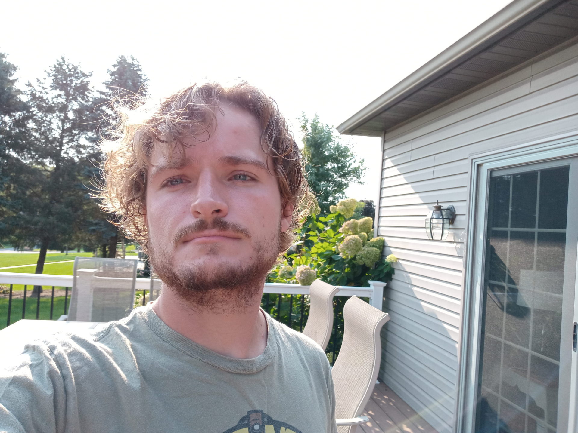 A standard selfie taken with the LG Reflect of a man with light hair and facial hair wearing a grey t-shirt, taken outdoors.
