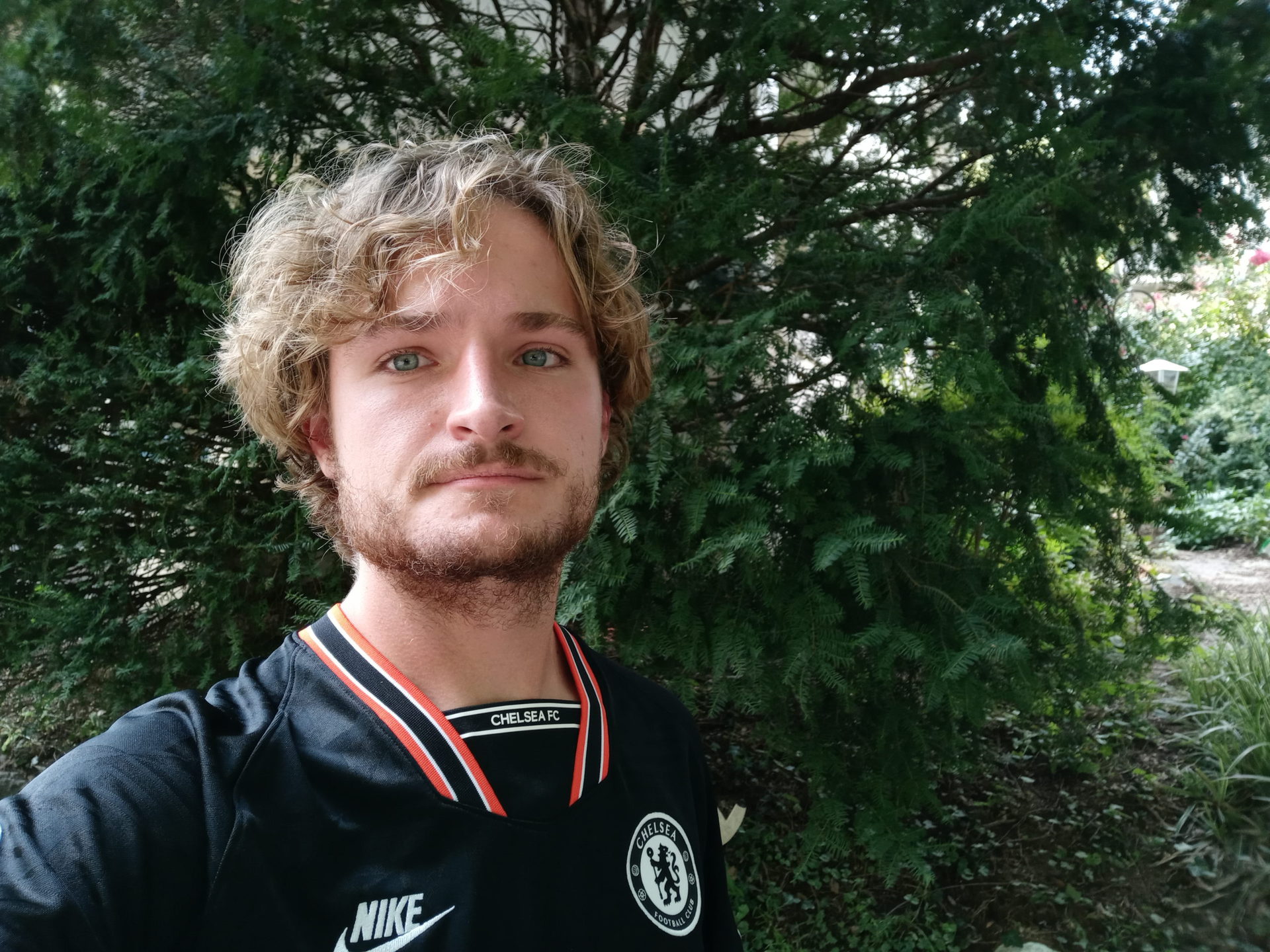 LG Stylo 6 standard selfie of a man with blonde curly hair and facial hair, wearing a dark coloured top.