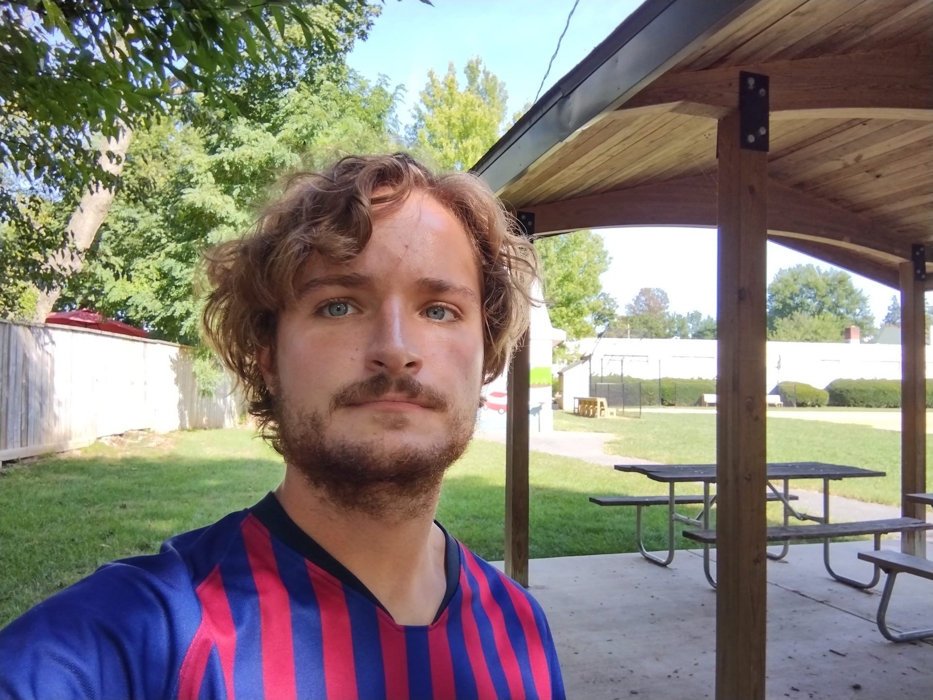 Motorola Moto G Power standard selfie of a man with light curly hair and facial hair wearing a blue and red striped top