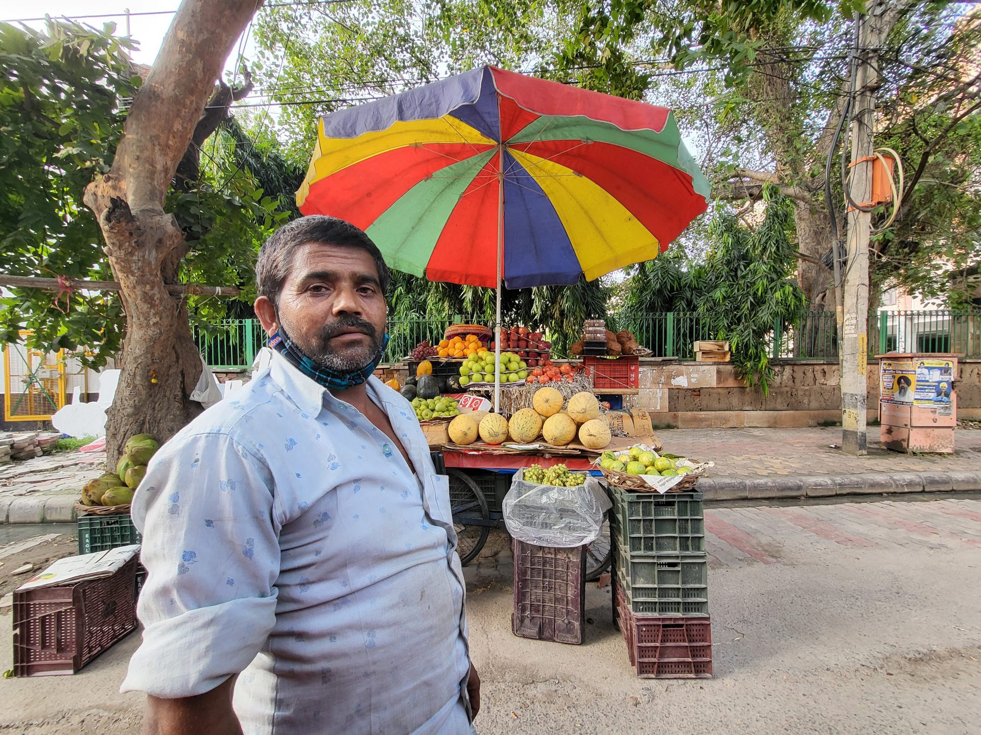 Samsung Galaxy Z Flip 3 ultrawide camera fruit seller man standing in front of his fruit stall with a colorful umbrella