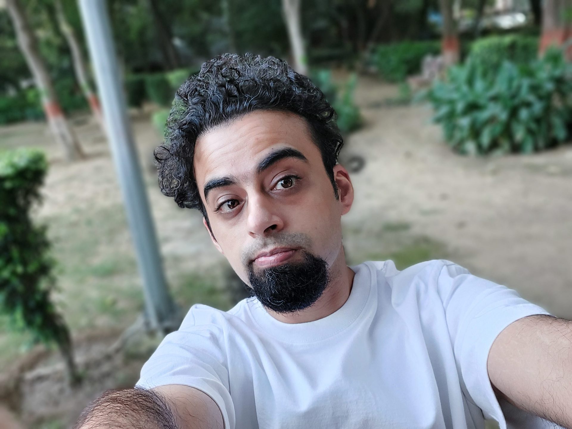 Samsung galaxy m52 camera sample selfie normal portrait of a man with dark curly hair and a beard wearing a white t-shirt outdoors