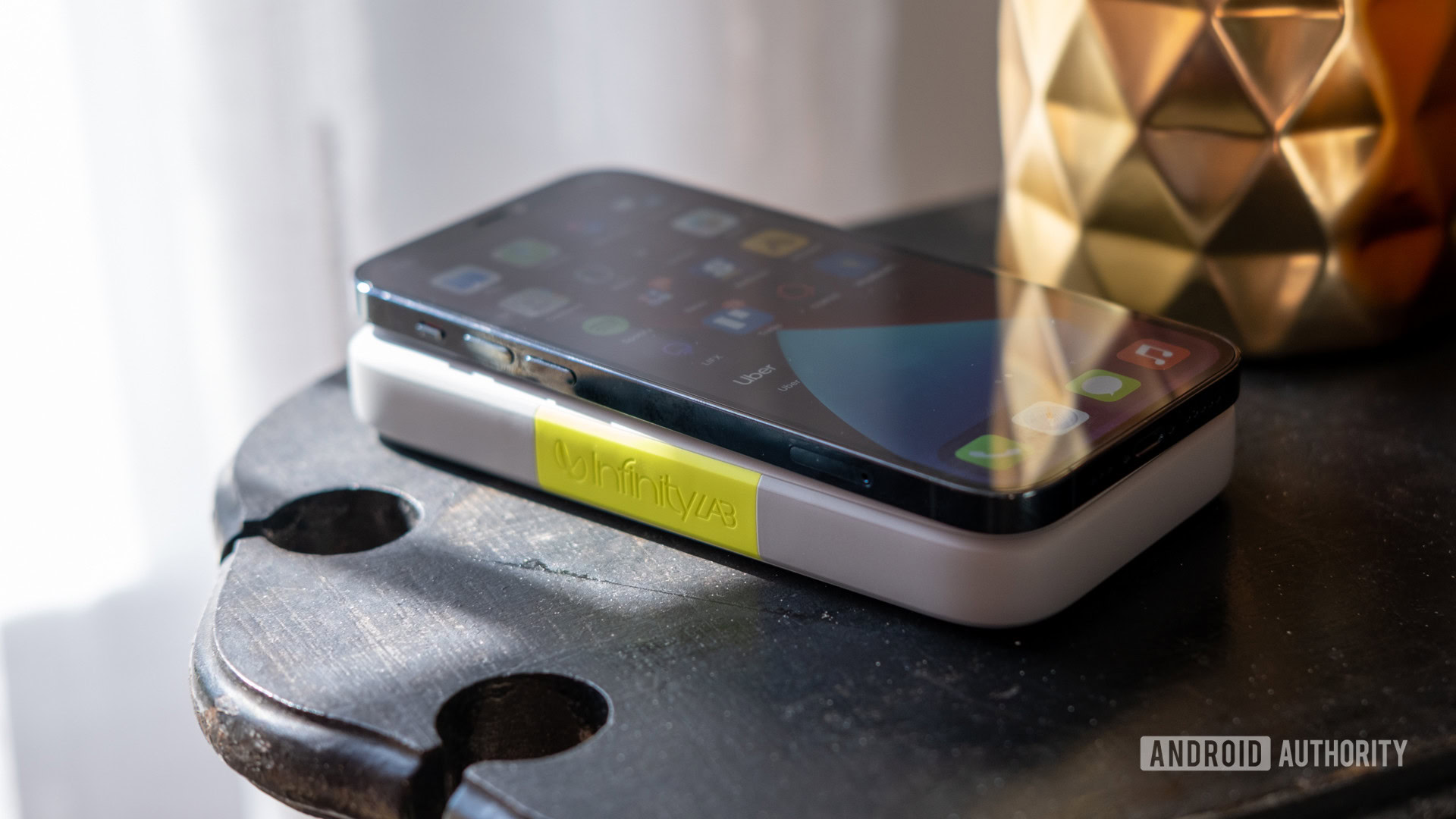 The InfinityLab InstantGo power bank wirelessly charging an iPhone 12 Pro
