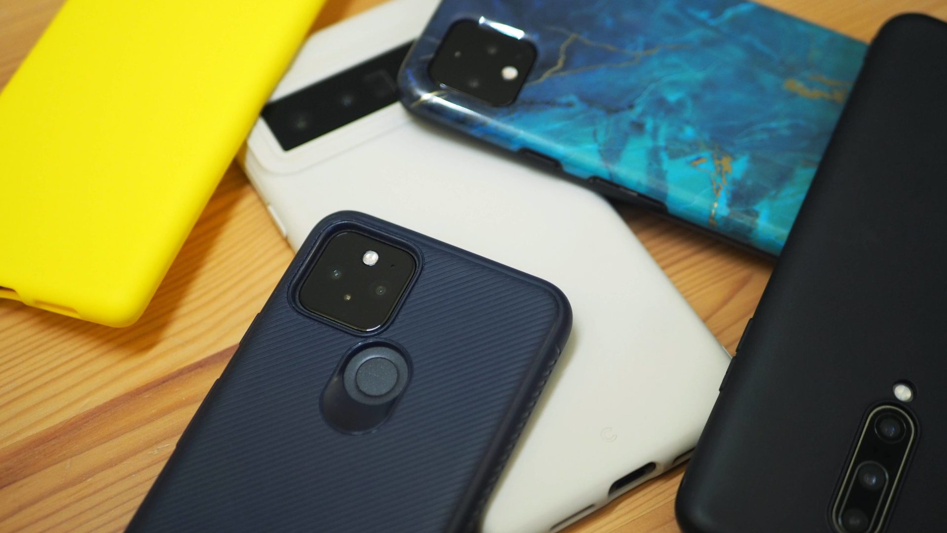 A collection of TPU phone cases in yellow, cream, navy, black, and marble green.