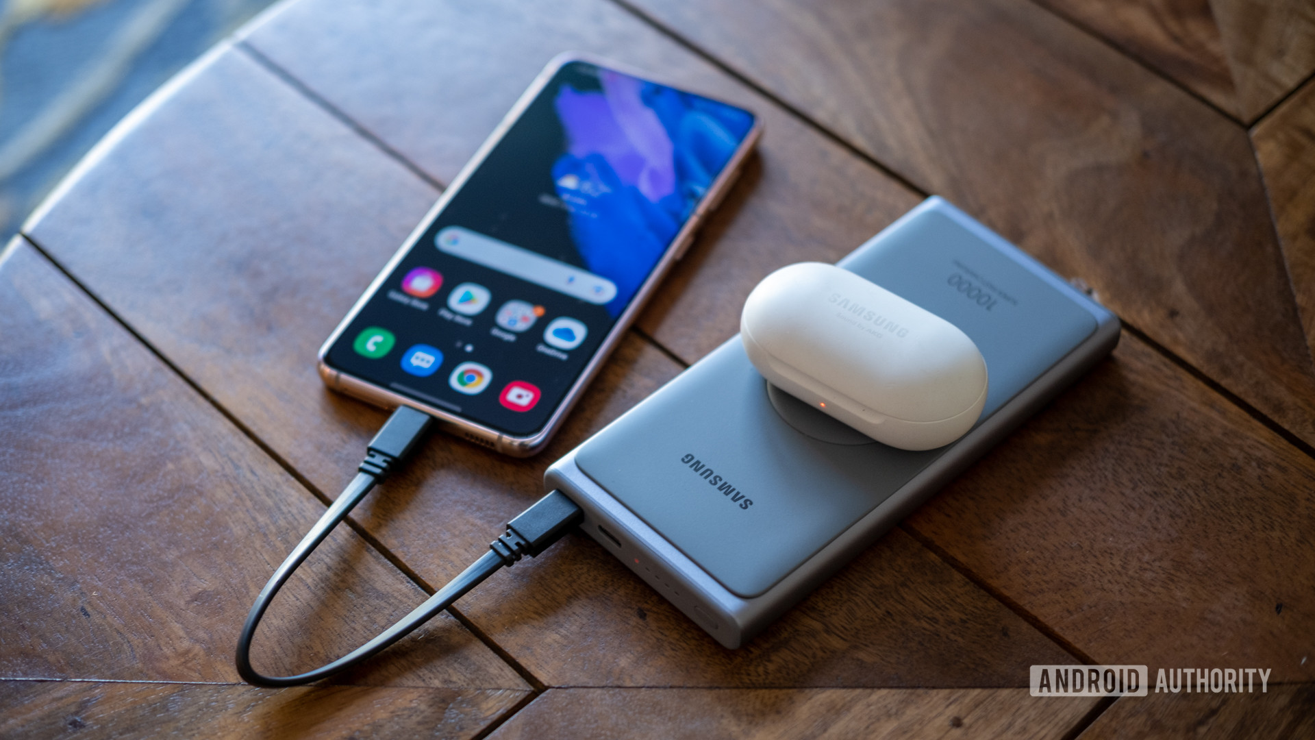 Samsung super fast power bank on table charging s21 and galaxy buds above