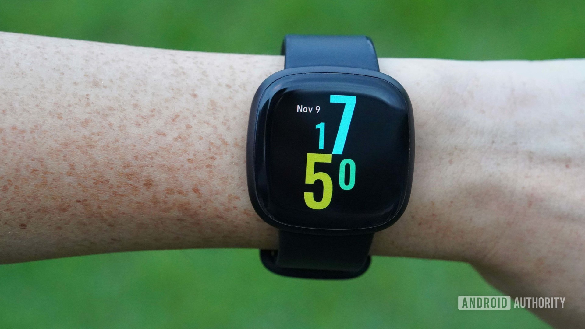 A Fitbit Versa 3 on a woman's wrist, displaying the Hawaiian Punch watch face.