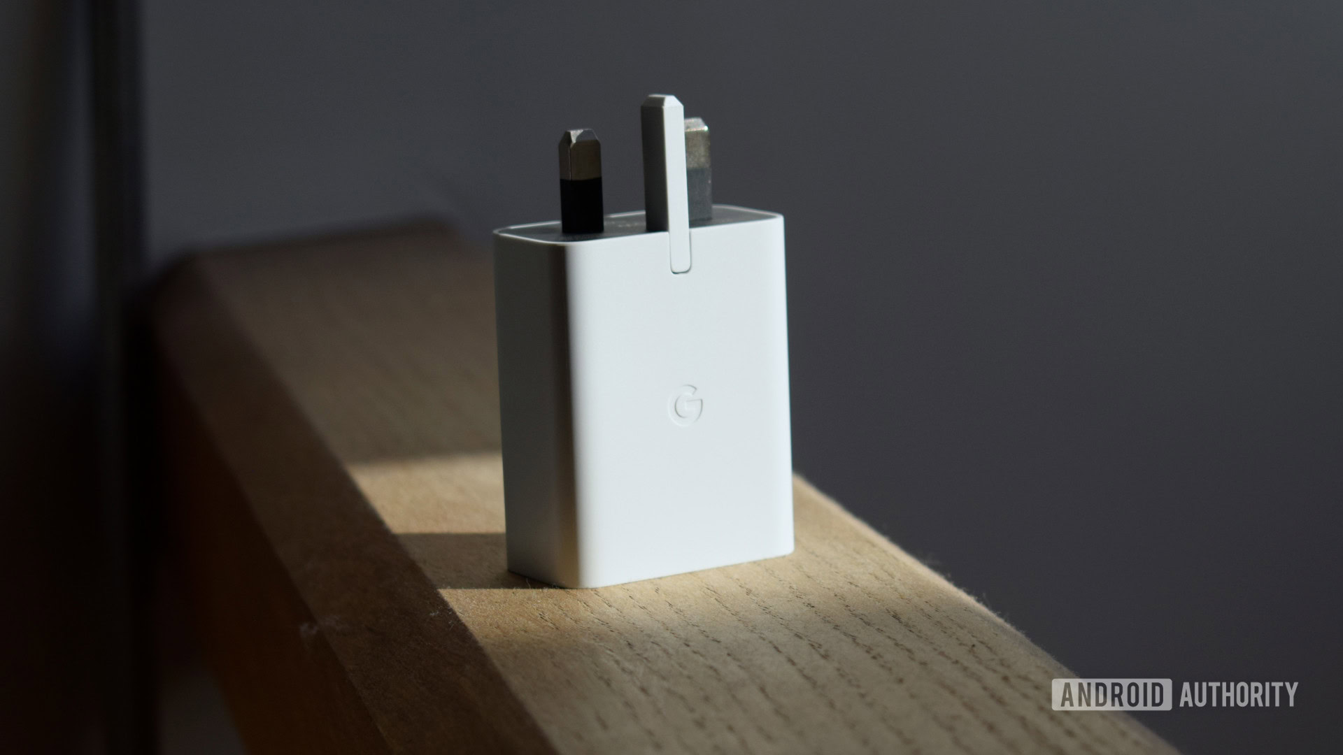 Google 30W USB-C Power Adapter standing upright on wooden beam
