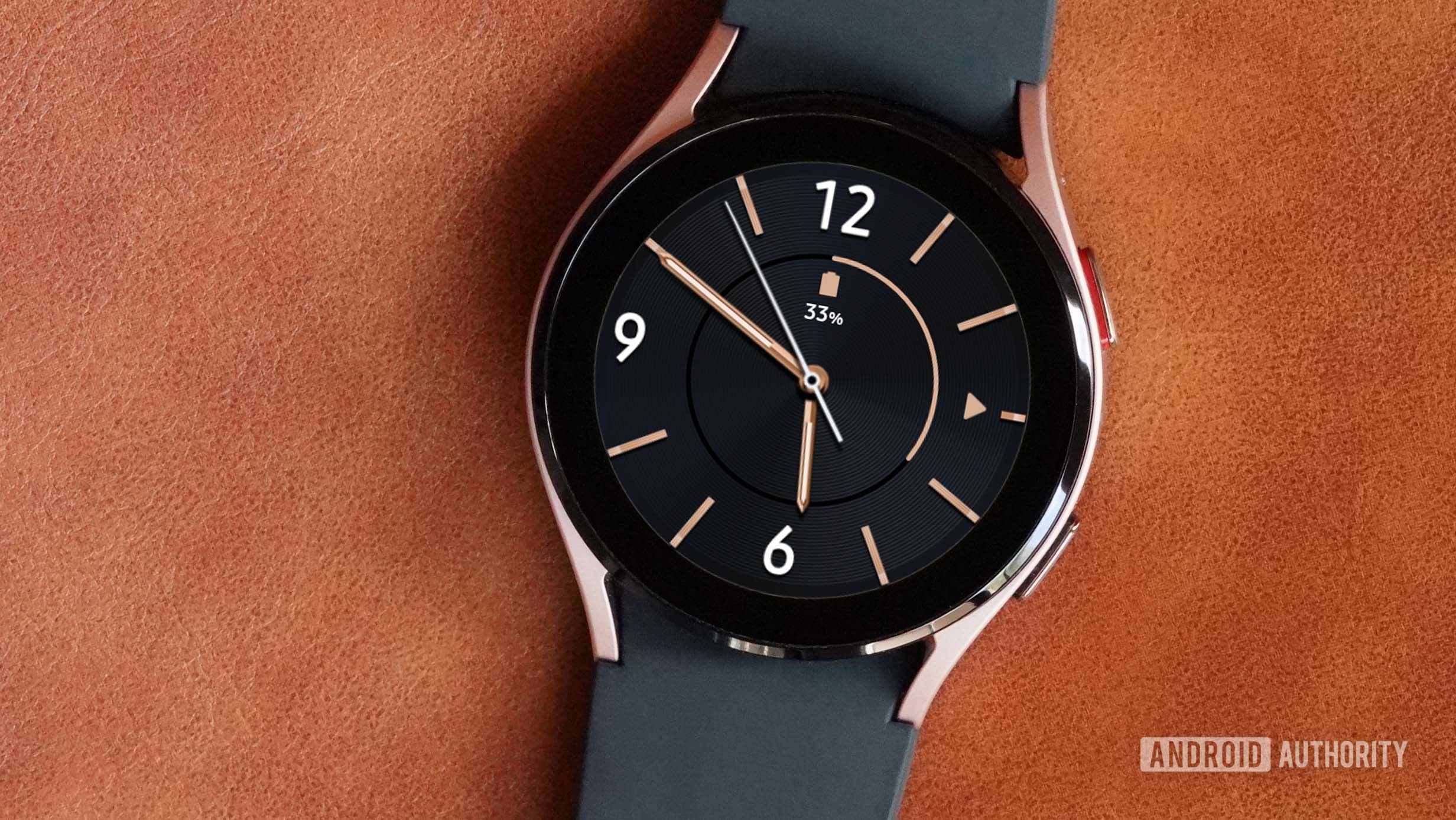 A Samsung Galaxy Watch 4 on a leather surface displays the watch face Modern Minimalist.