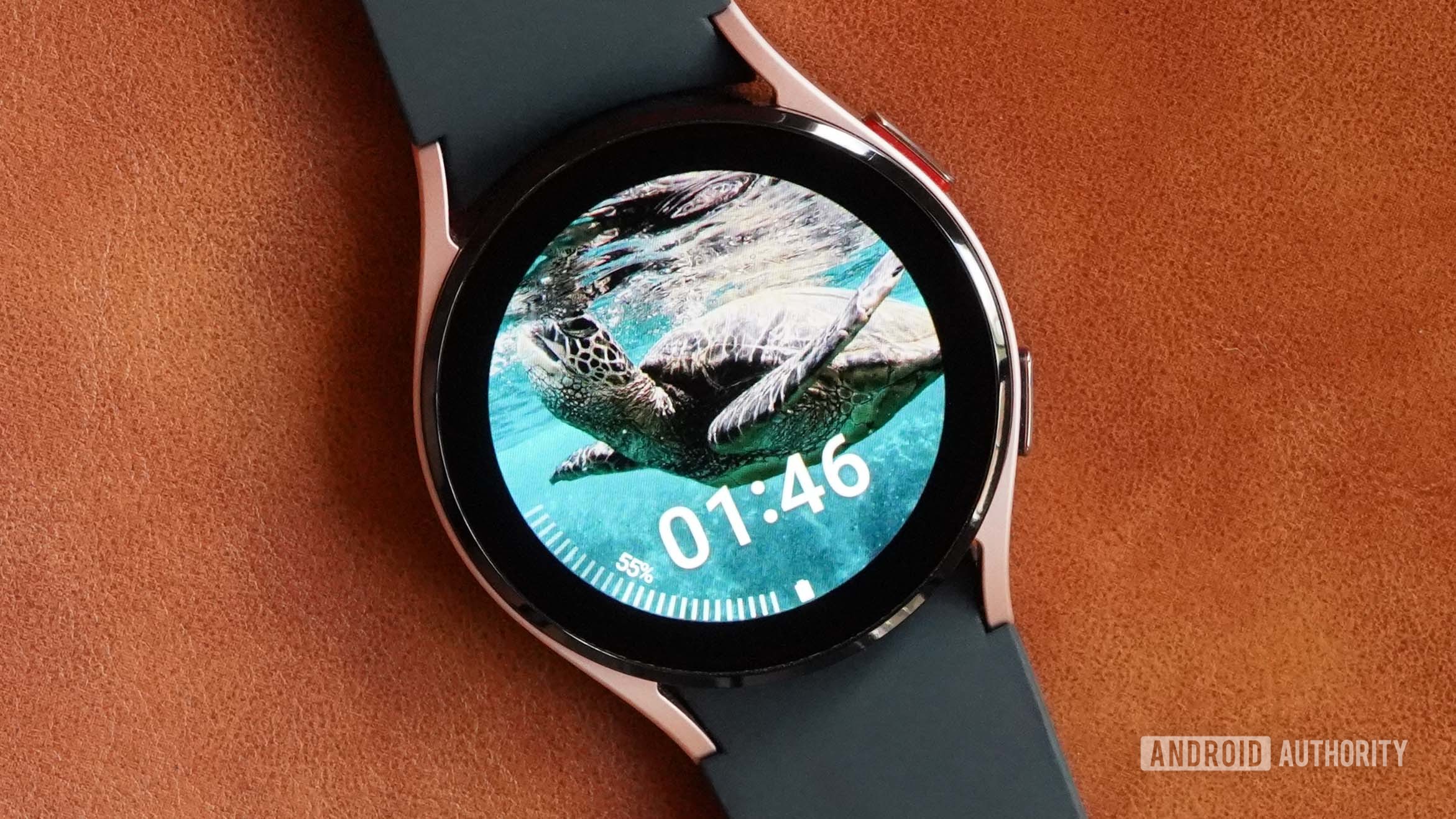 A samsung galaxy watch 4 on a leather surface displays the watch face my photo+.