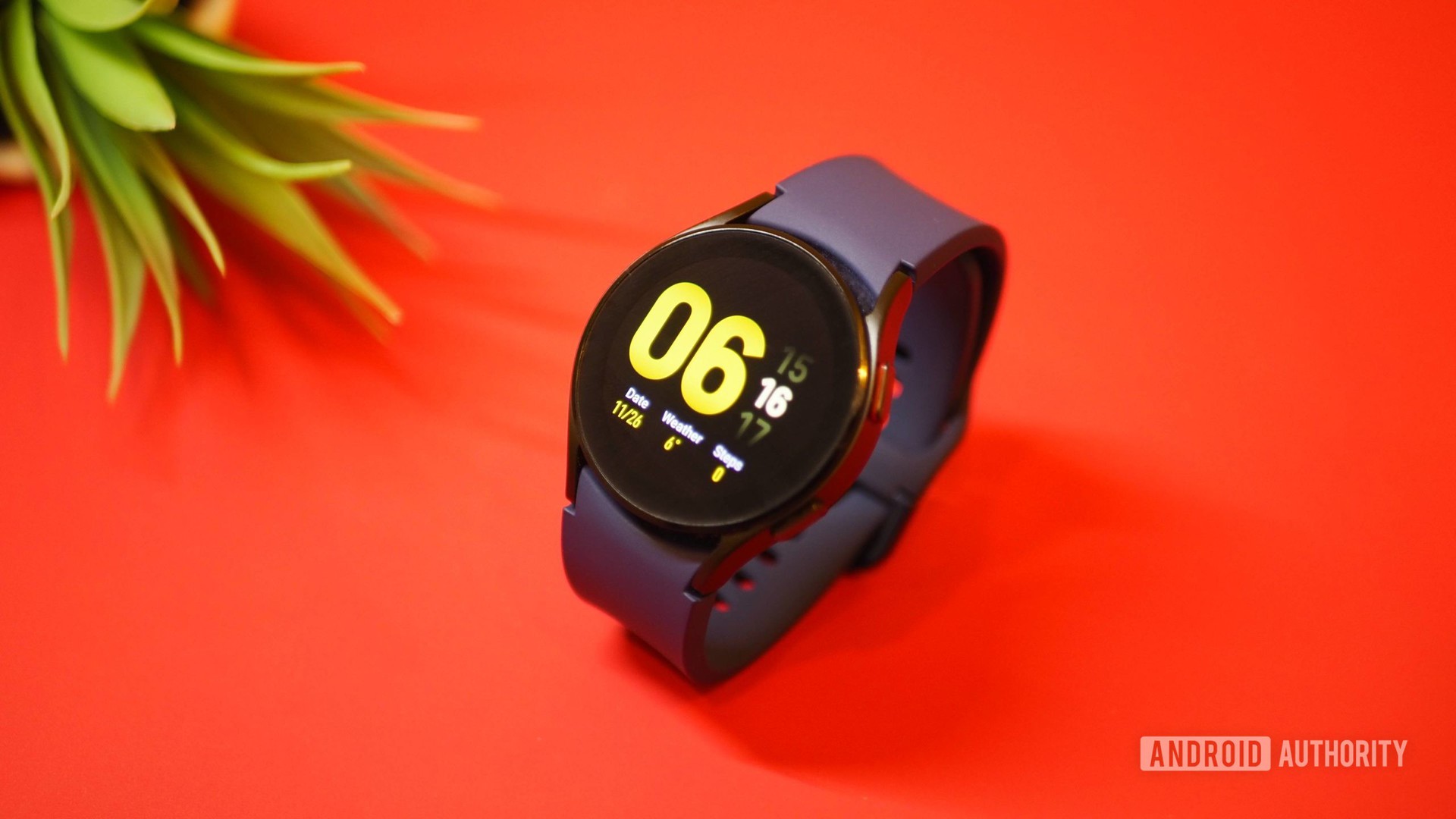 Samsung Galaxy Watch 4 on red background, showing homescreen clock