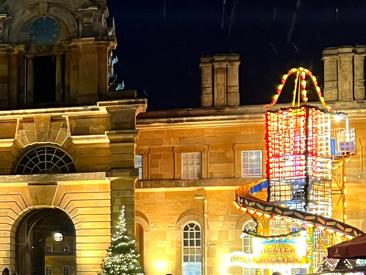 Crop of lit up stone building and fairground ride at night shot on Apple iPhone 13 Pro Max