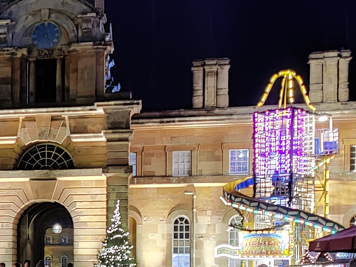Crop of lit up stone building and fairground ride at night shot on OnePlus 9 Pro