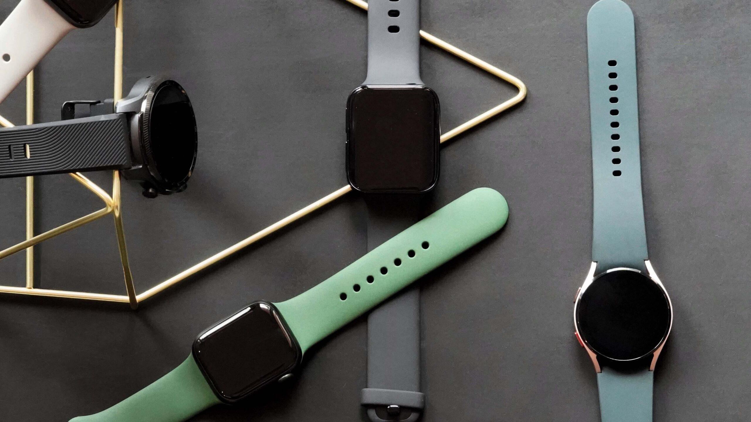 Un mélange de Wear OS et de montres Apple repose sur un tapis en caoutchouc noir, illustrant un mélange d'options de montres carrées et circulaires.