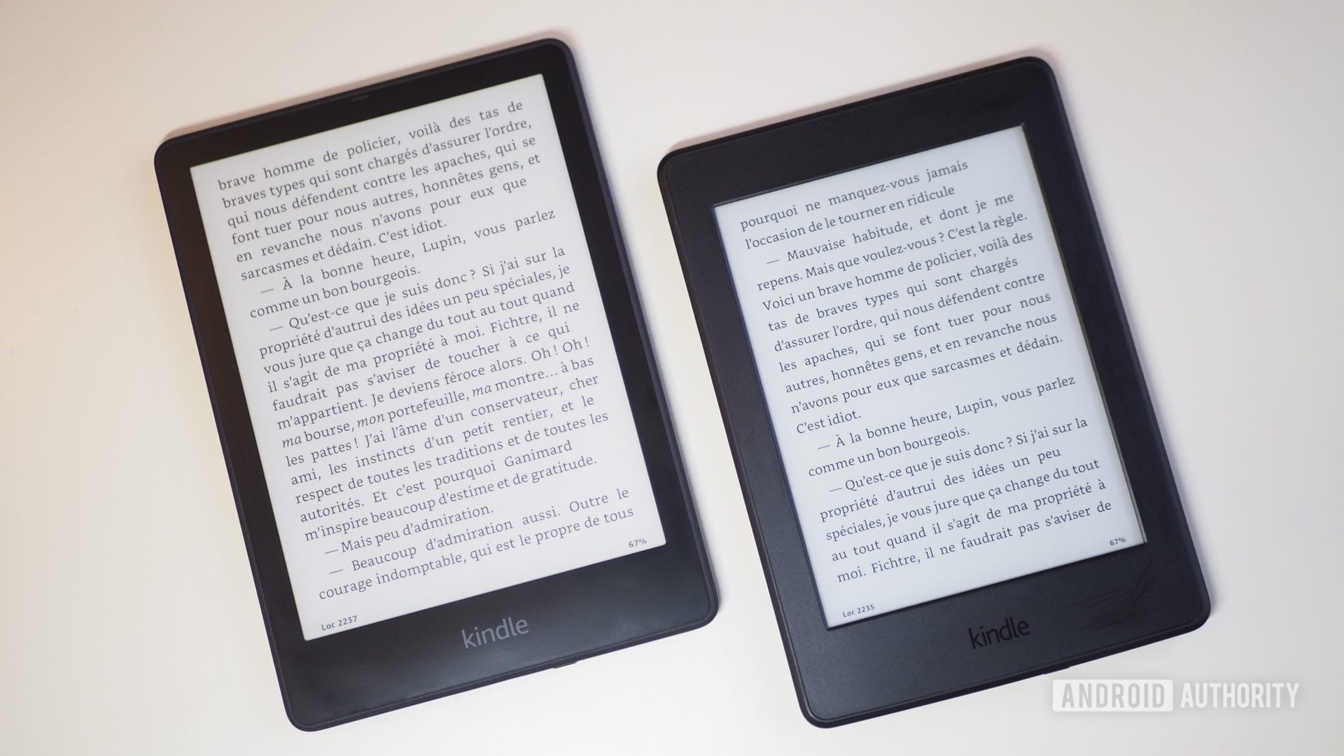 Amazon Kindle Paperwhite 2021 next to Paperwhite 2015, laying on a table, showing a book
