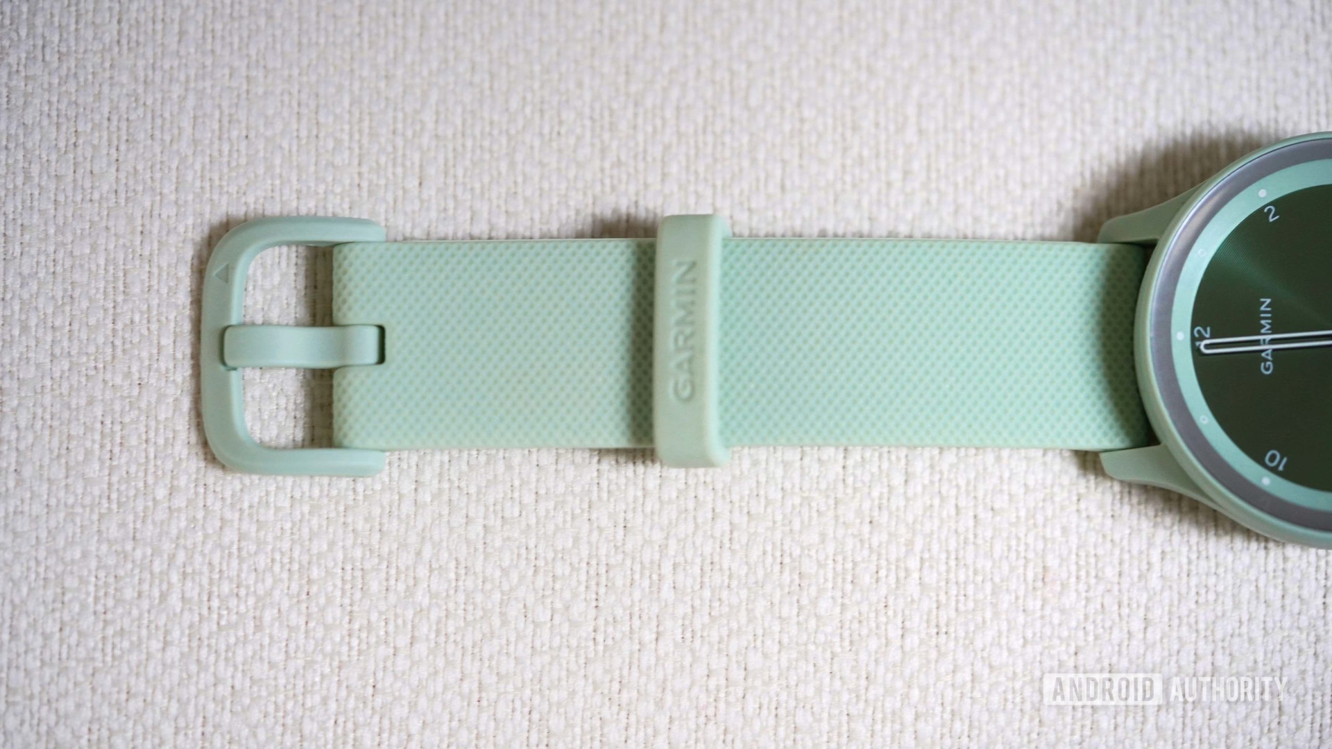 A close up of the Garmin Vivomove Sport's band, showing the plastic buckle in soft green.