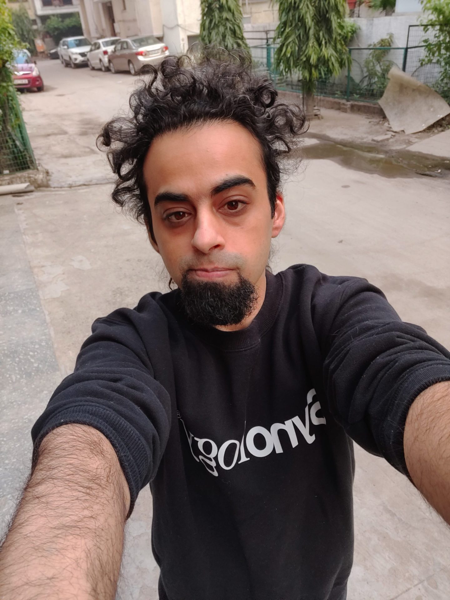 OnePlus 9RT selfie camera normal outfoor selfie of a man with dark curly hair and a beard, wearing a black top